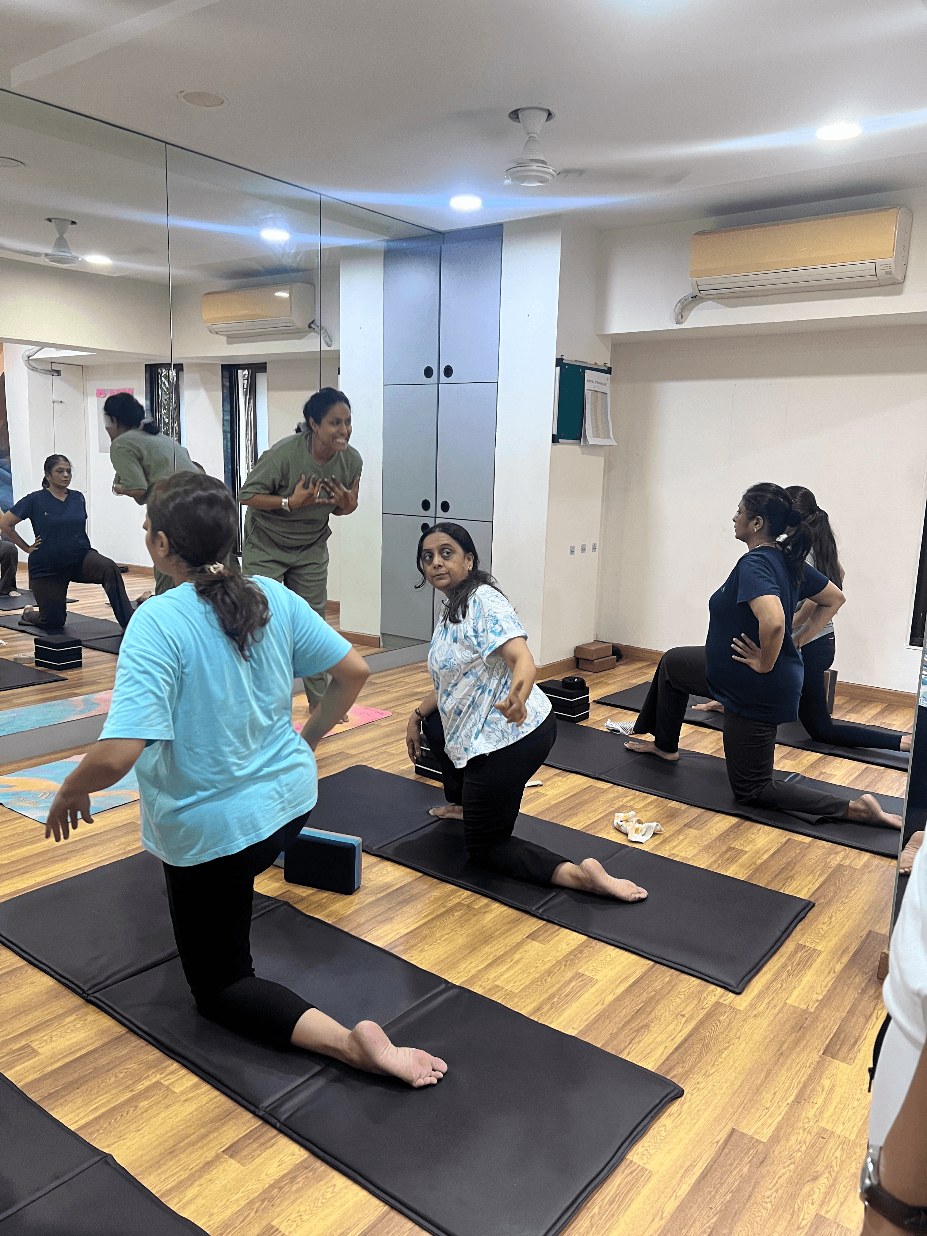 Mayuri guiding students into a low lunge stance in class